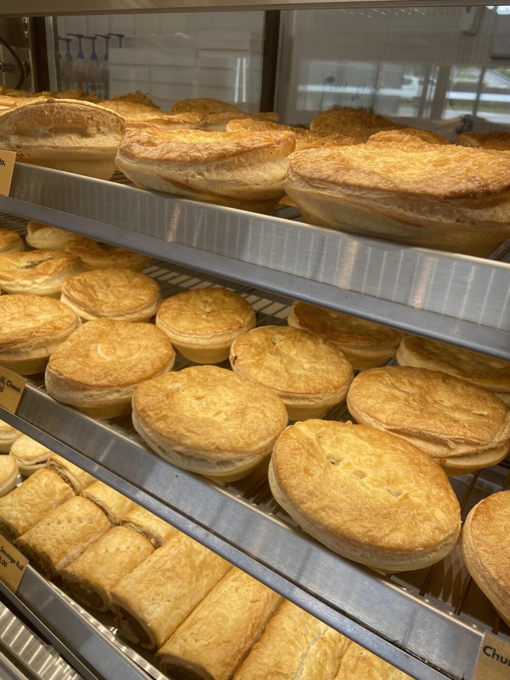 Rows of golden pies on metal shelves in the cabinet, each with a small black label